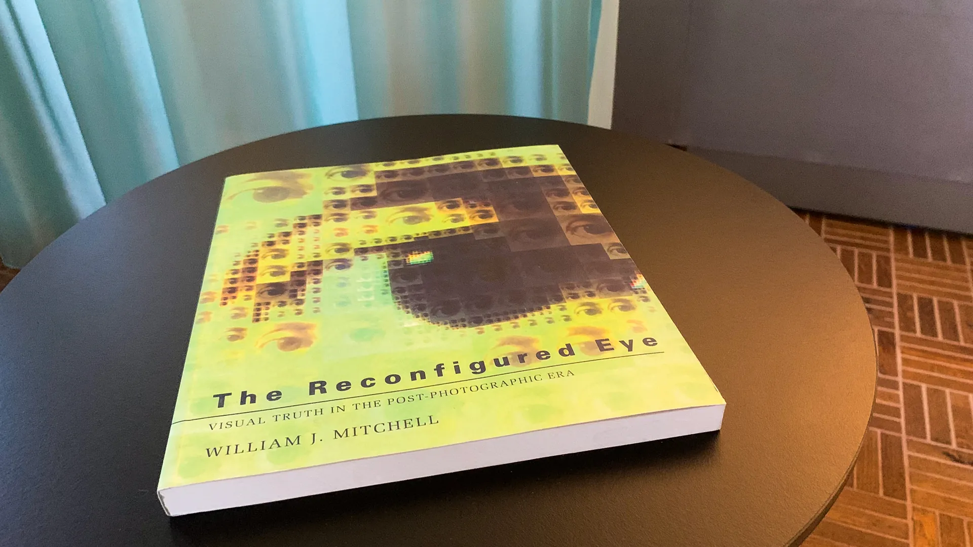 Buch «The Reconfigured Eye – Visual Truth in the Post-Photographic Era» von William J. Mitchell auf einem runden schwarzen Tisch