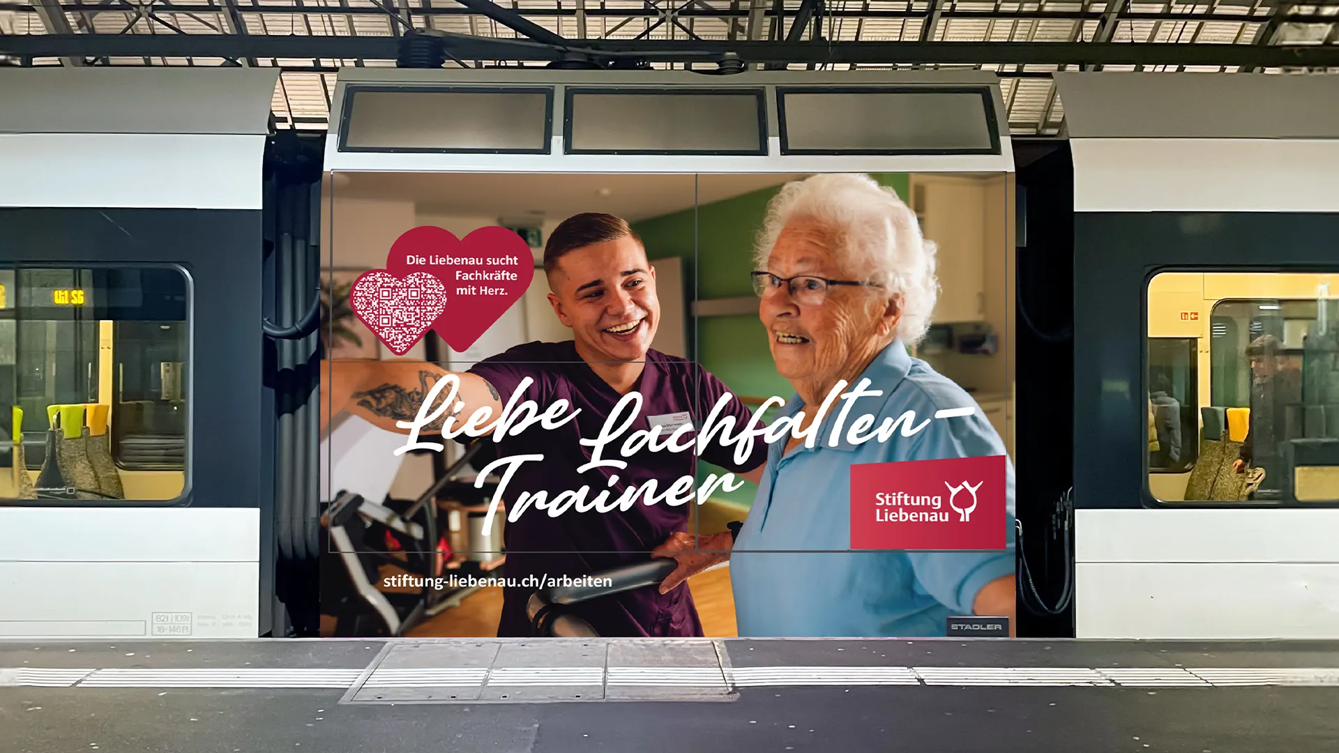Bahnwerbung der Stiftung Liebenau: Pfleger und ältere Frau lachen gemeinsam, darüber der Schriftzug «Liebe Lachfalten-Trainer»