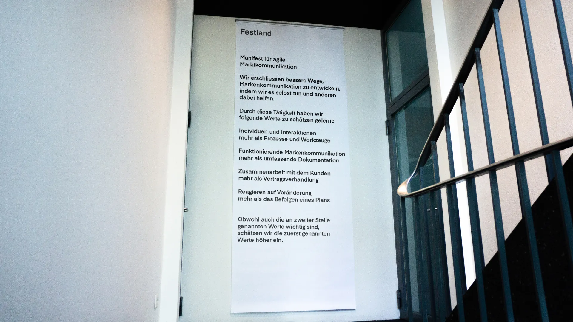 Banner im Treppenhaus von Festland mit dem «Manifest für agile Markenkommunikation» und seinen vier Wertepaaren