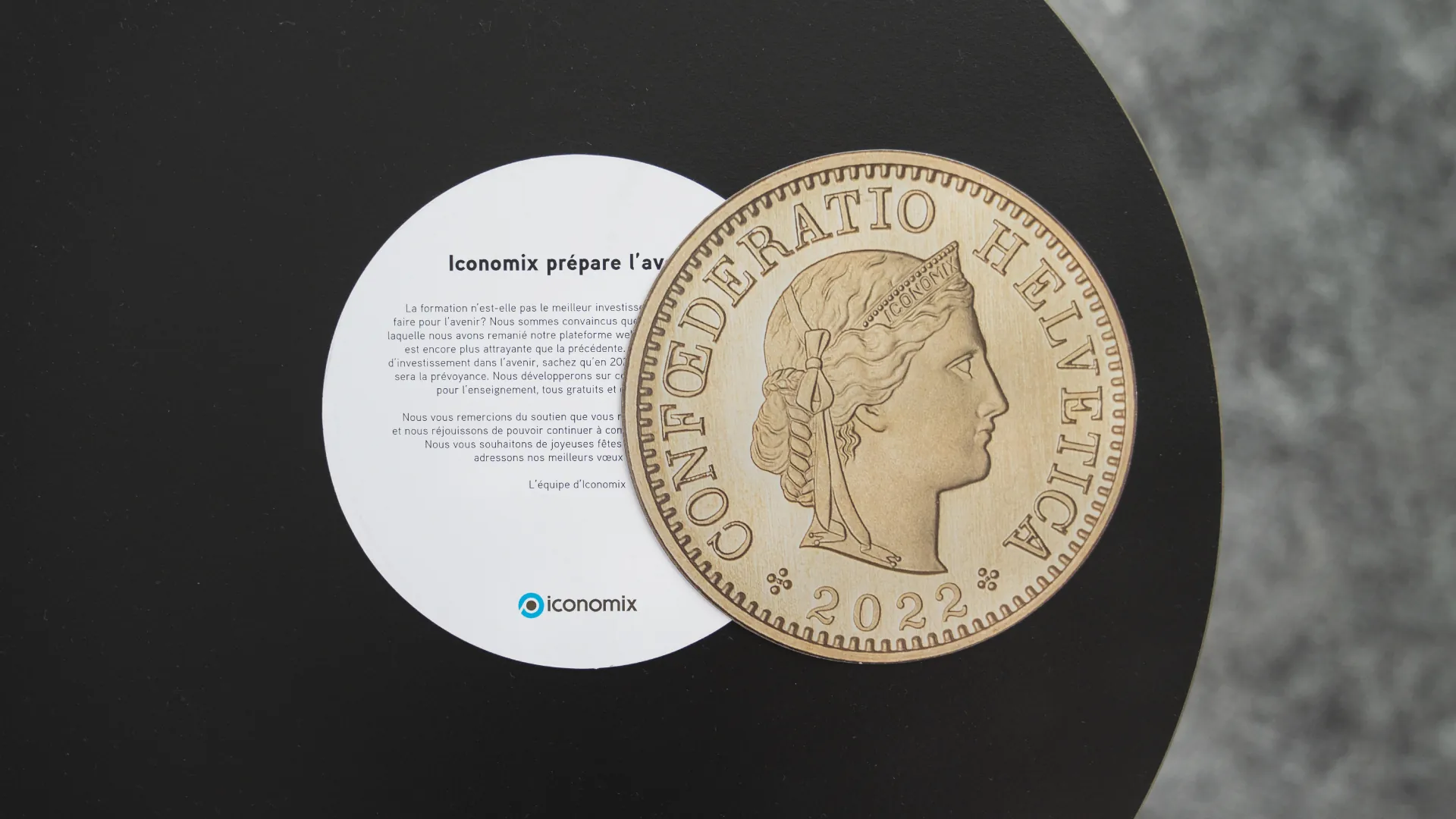 Neujahrskarte von Iconomix mit einem überdimensionierten Fünfräppler von 2022 und Grusstext «Iconomix prépare l’avenir»