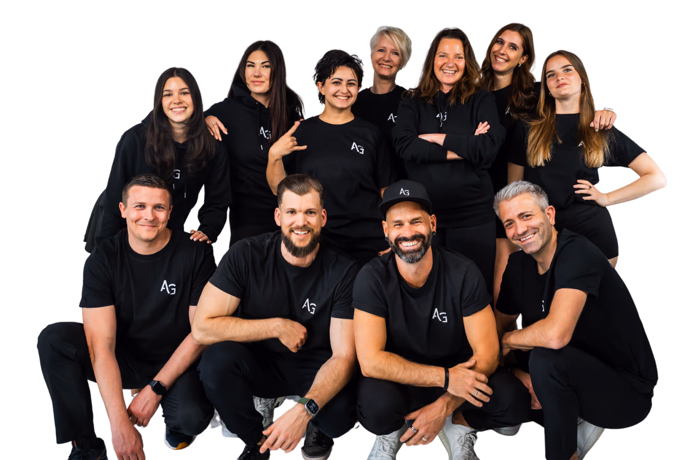 Group of eleven smiling adults wearing black AG logo shirts posing together.