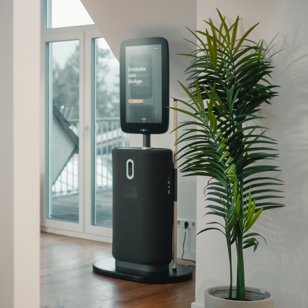Modern black fitness equipment with a digital screen showing user metrics and a connected weight machine with adjustable seat and handles.