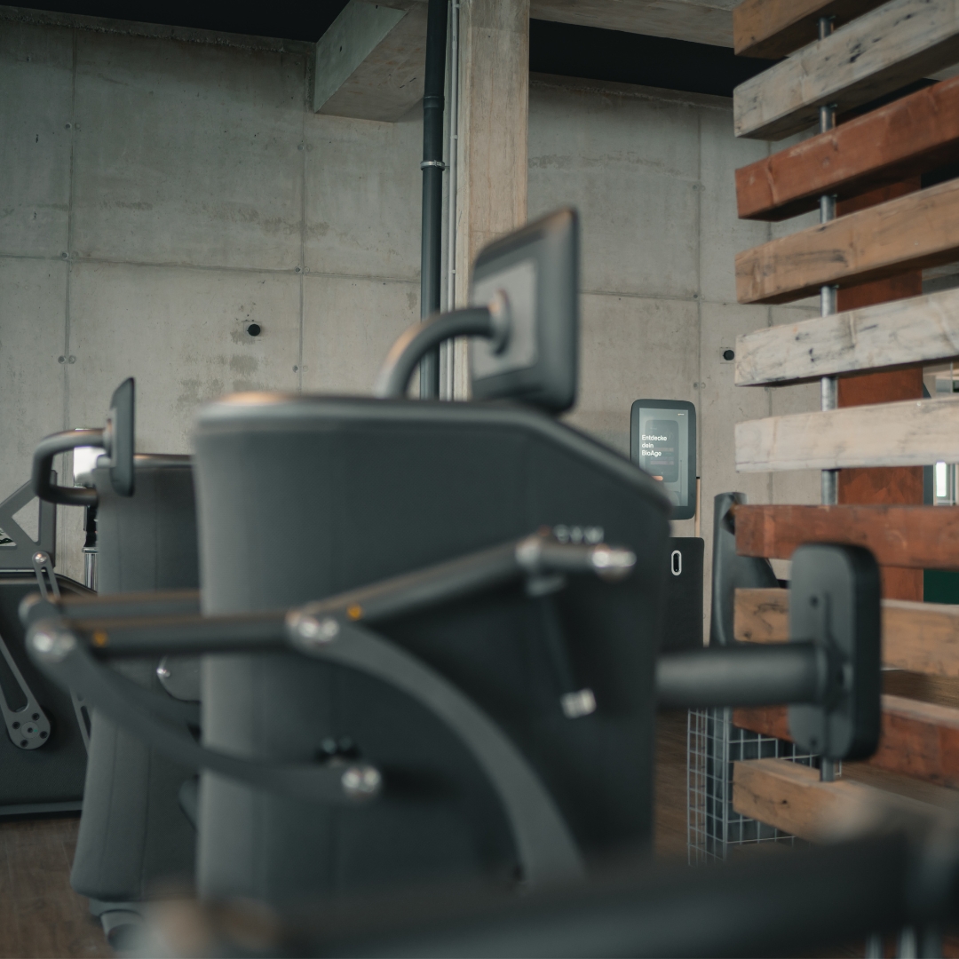 Gym interior with weightlifting equipment and motivational text in German translating to 'You only have one body... Make it a priority!'