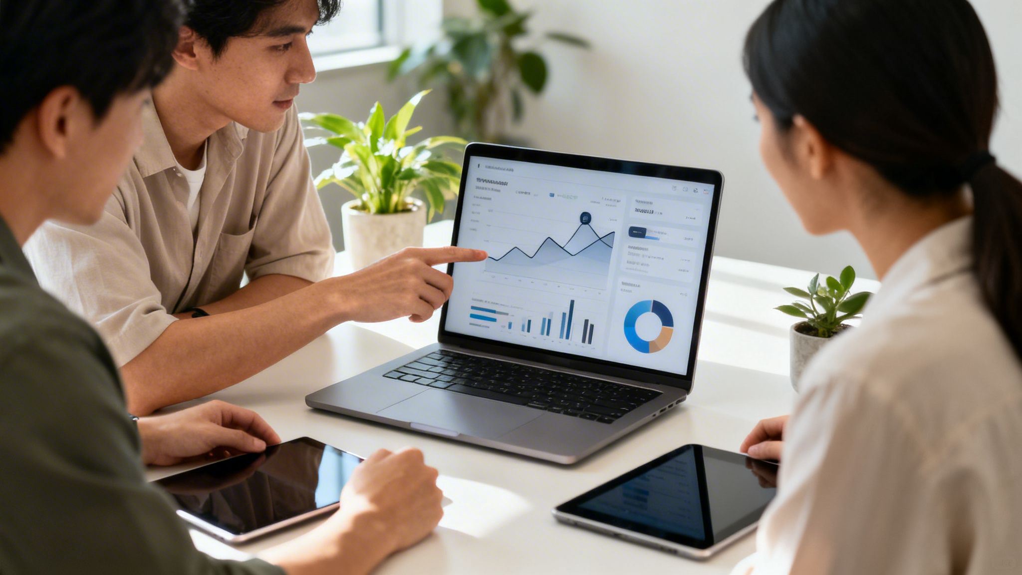 Drei Kollegen analysieren Geschäftsdaten und Grafiken auf einem Laptop in einem modernen Büro und diskutieren Ergebnisse.