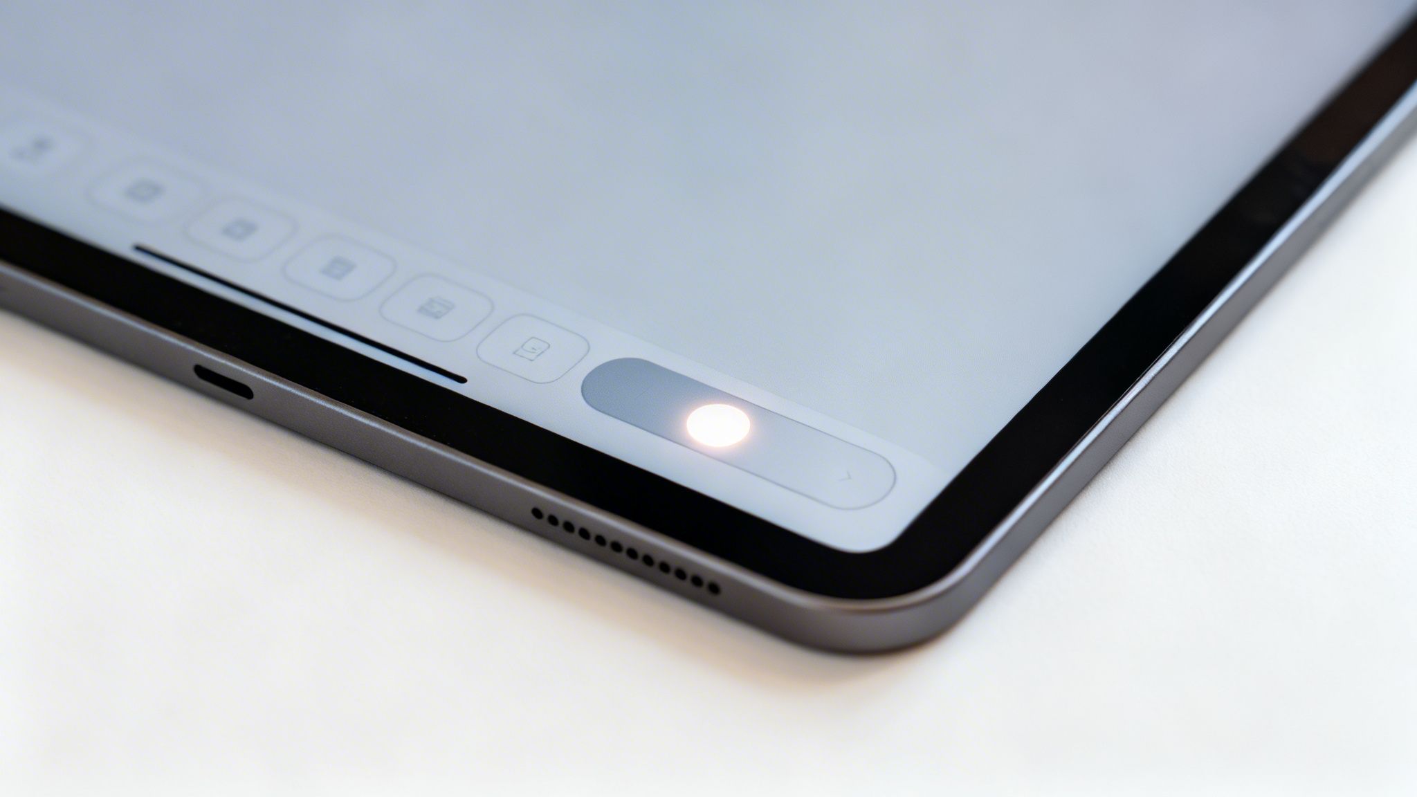 Nahaufnahme eines Tablets mit leuchtendem Schieberegler auf dem Bildschirm und Anschlüssen an der Seite.