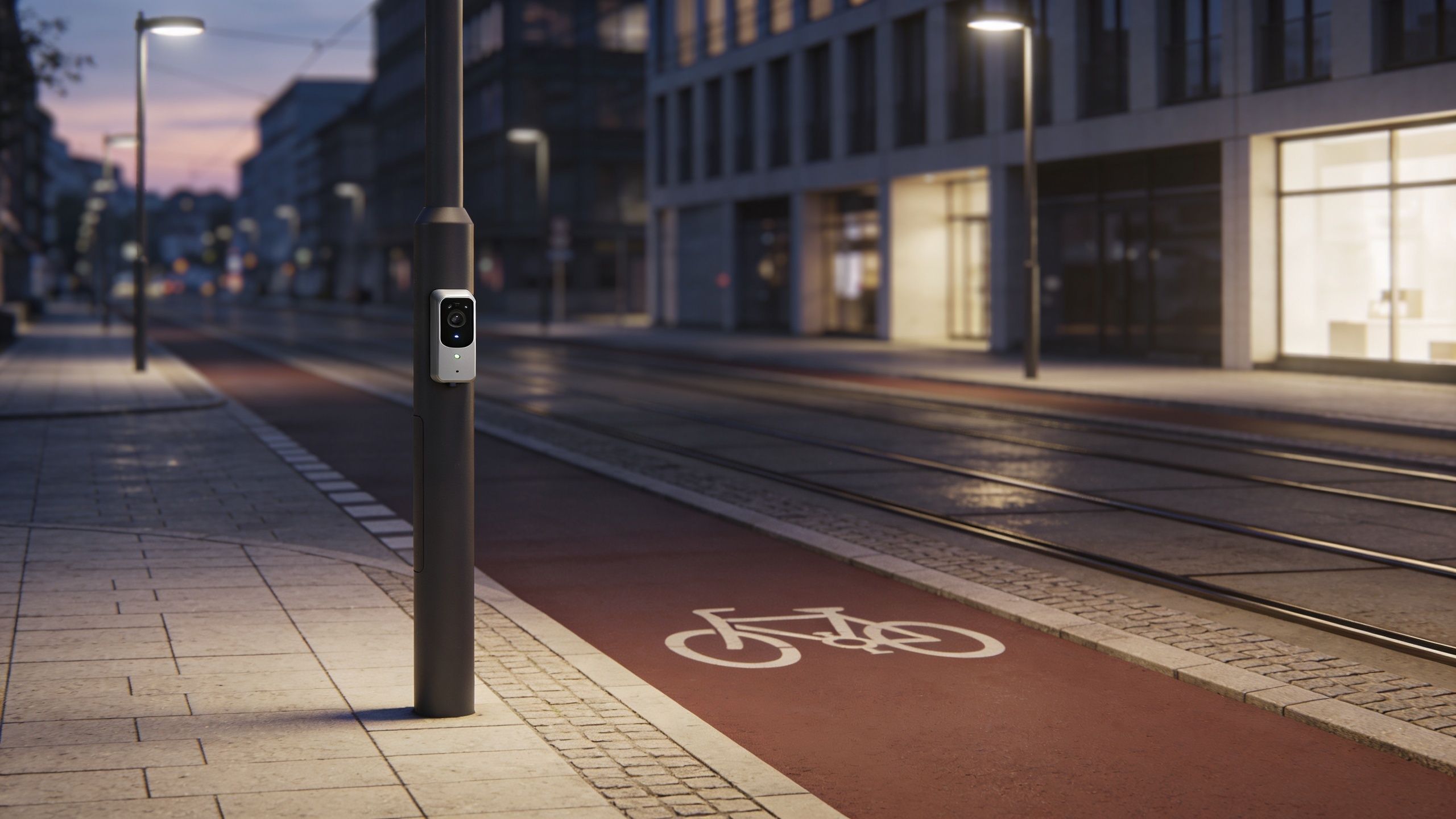 Eine moderne Überwachungskamera an einem Laternenmast neben einem Radweg in einer städtischen Umgebung bei Dämmerung.