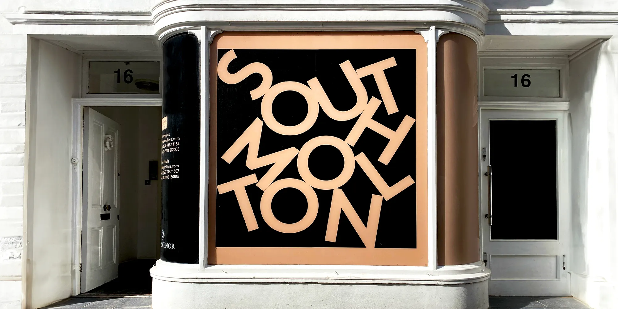 Shopfront featuring bold beige lettering on a black background spelling "South Molton," with white doors on either side.