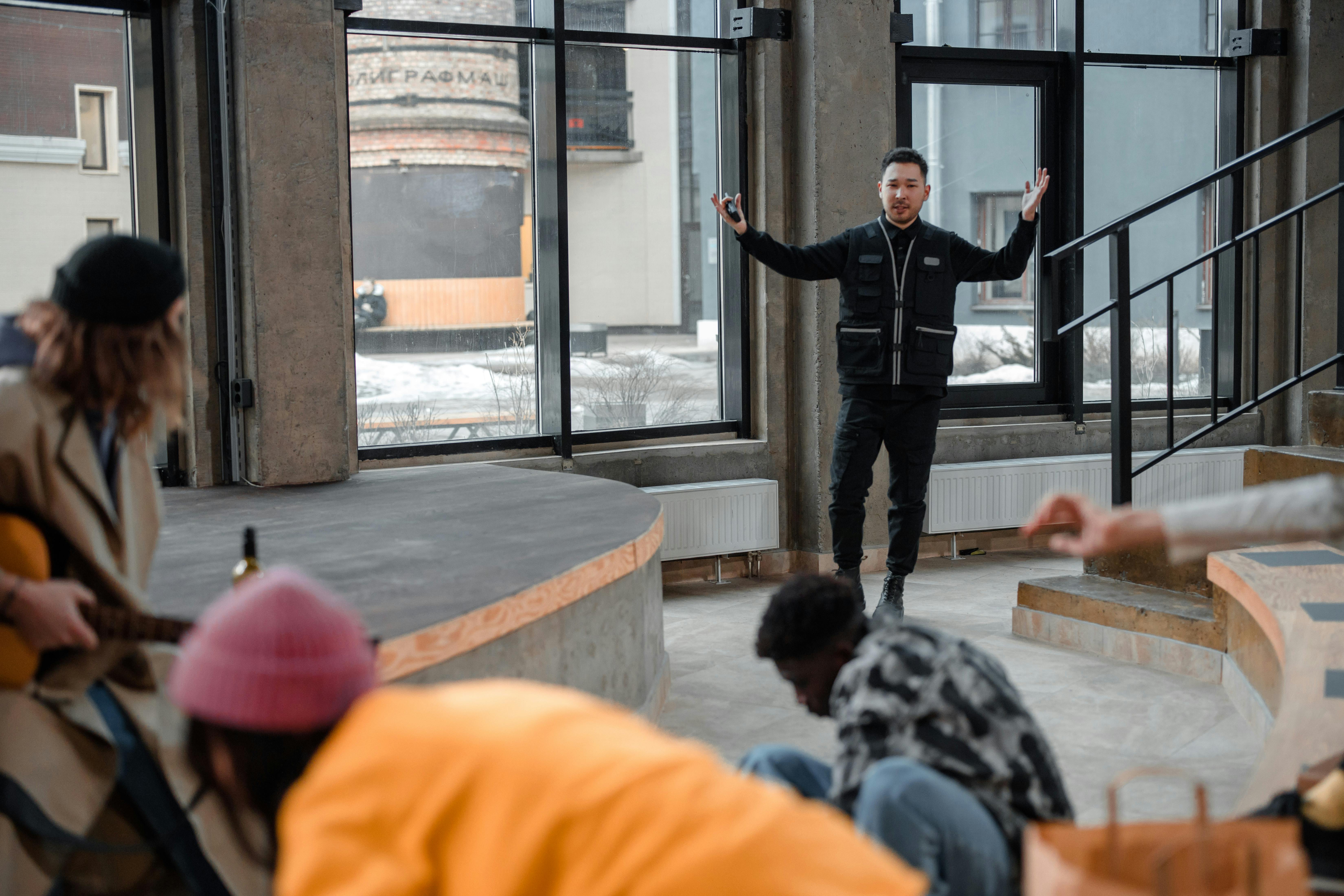 People congregate in a contemporary indoor amphitheater, with a person seeming to guide or perform.