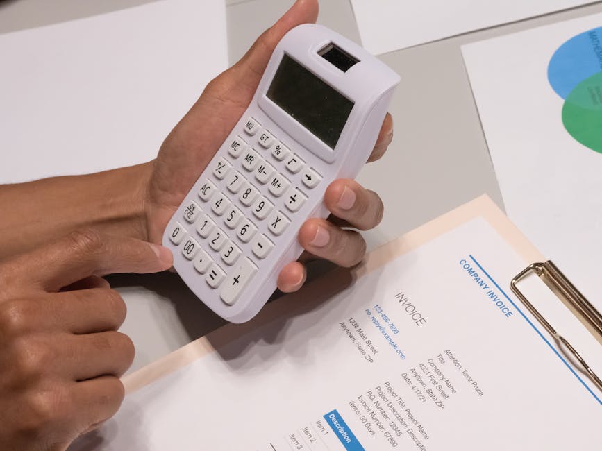 Close-up of hands using a calculator next to a company invoice, depicting a financial calculation concept.
