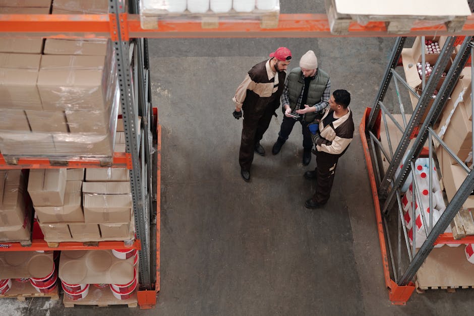 Three warehouse workers discussing logistics in an industrial storage area.