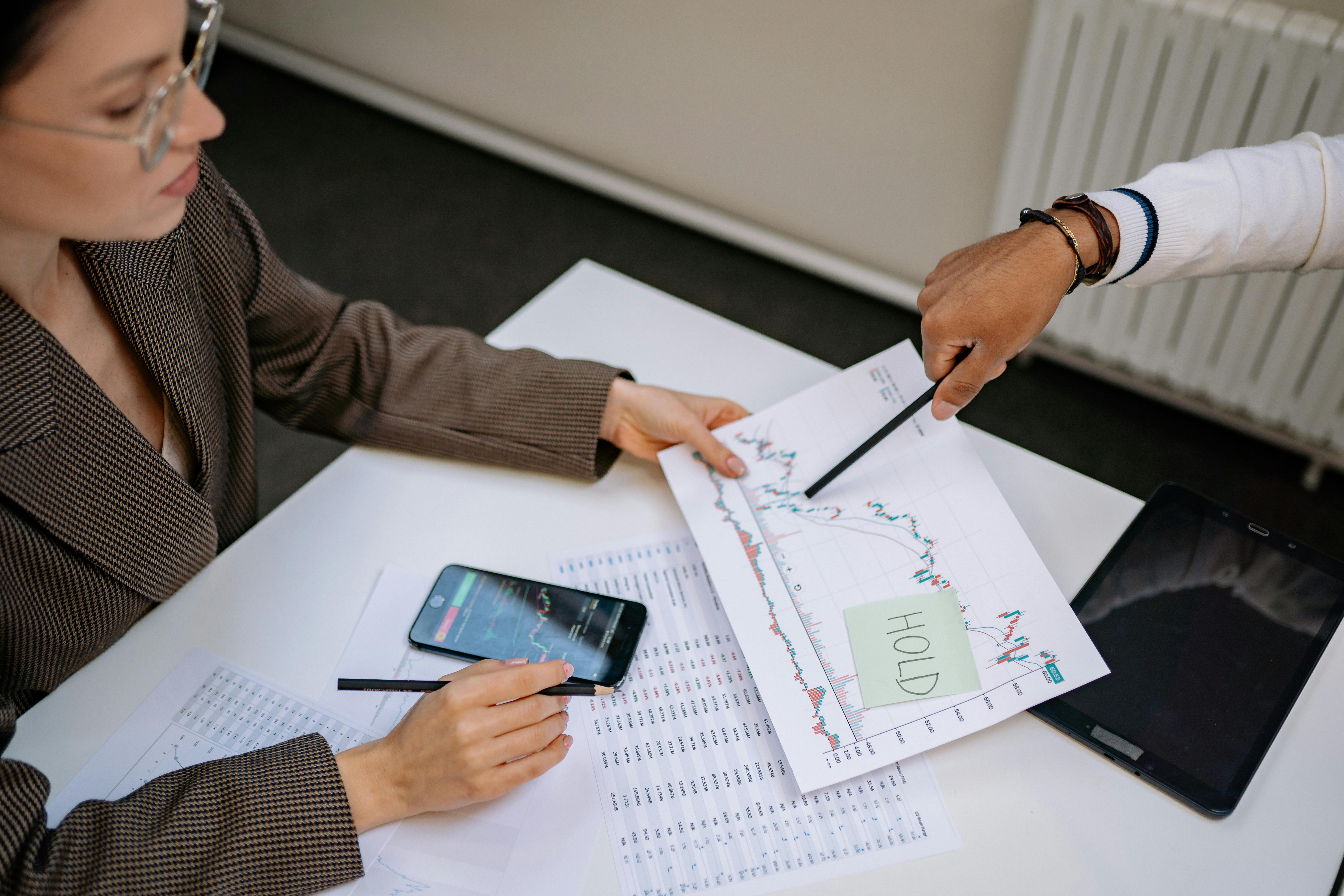 Two professionals analyzing stock market data and graphs at a desk.