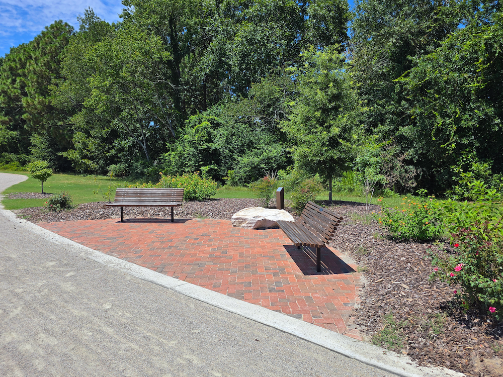 Brick seating area with benches and landscaped planting along the walking trail at Hardee Lane Park in Whispering Pines, North Carolina.