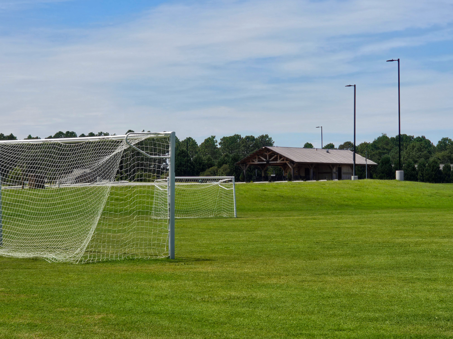 Multi-purpose athletic fields with soccer goals and pavilion at Hardee Lane Park in Whispering Pines, North Carolina, designed for community recreation and amenity use.