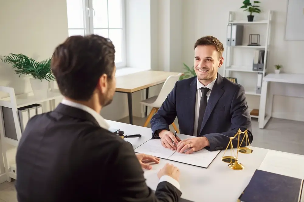 lawyer sitting with client at a desk in a bright room