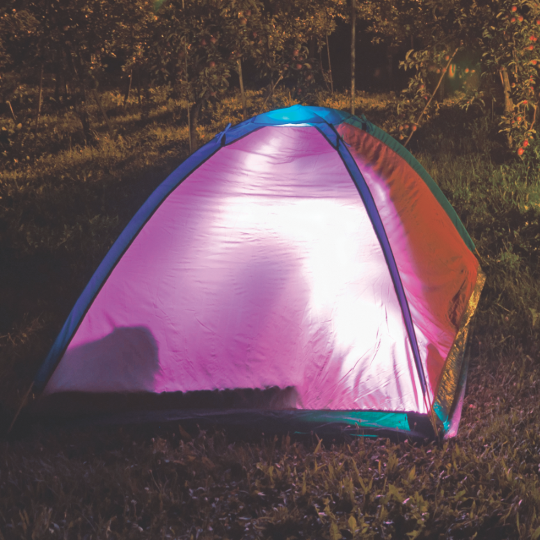 Purple tent in outdoor night scene, glowing from its interior light.