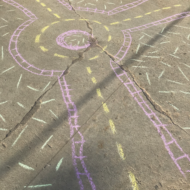 Purple and yellow chalk drawings on an asphalt surface.