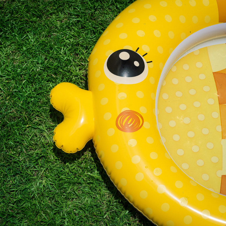 Close-up of an inflatable fish-shaped pool on a grassy surface.