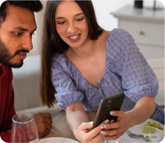 Diners at a restaurant table using a phone to order and pay