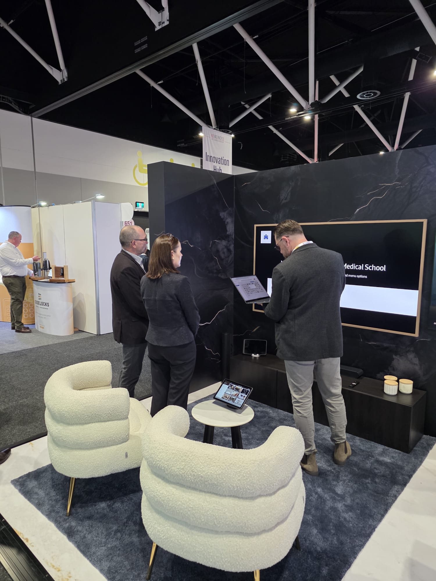 Visitors trying the Samsung and Payflo hotel demo on a tablet at the Samsung booth, No Vacancy Hotel Expo