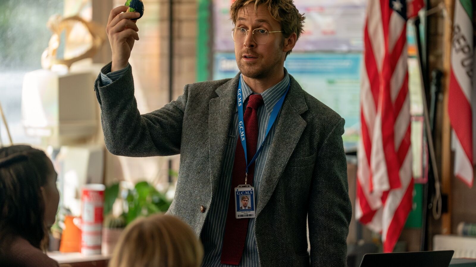 Ryan Gosling as a science teacher holds up an object in a classroom in a scene from Project Hail Mary.