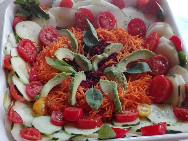 Saladier avec une salade composée. Il y a des carottes, des tomates, du concombre. 