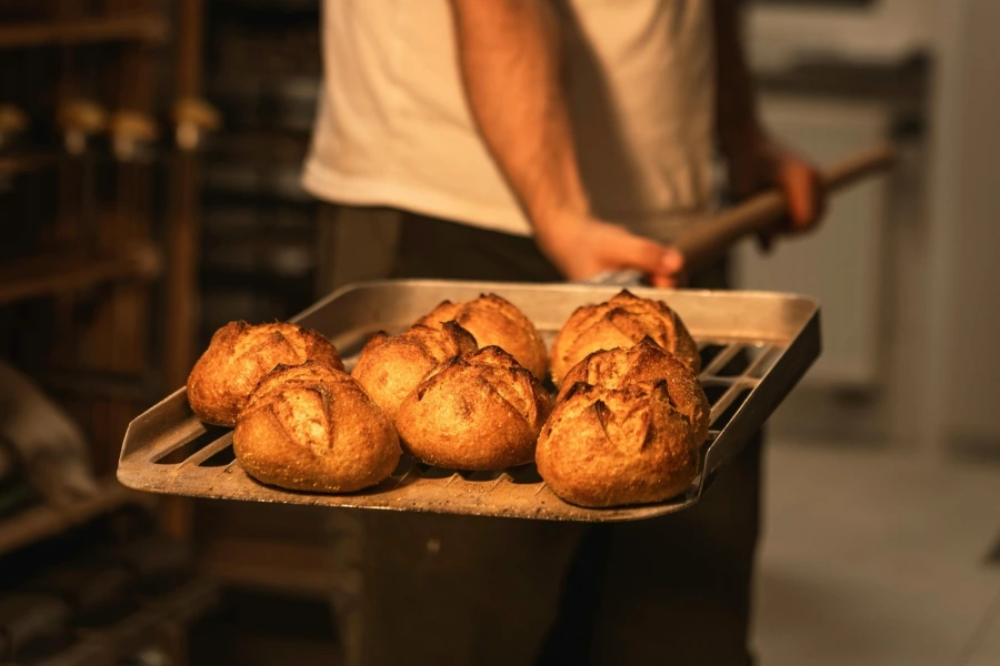 Un boulanger met des pains au levain dans un four à l'aide d'une pelle.
