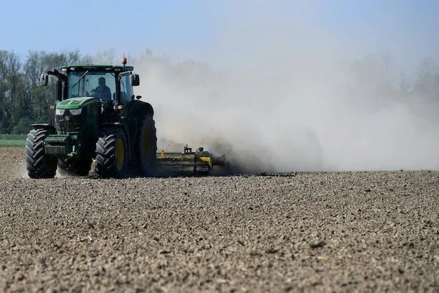 Paysage de culture aride, le sol est nu et sec. Aucunes cultures ne poussent. On voit un tracteur.