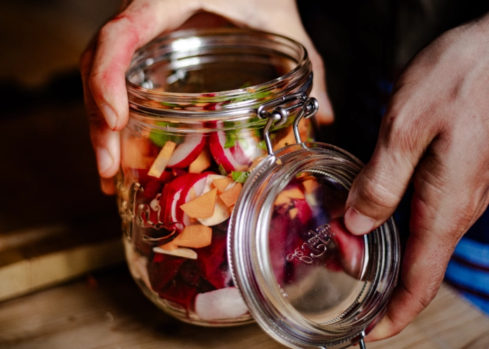 Mains tenant un bocal de légumes lactofermentés prêt à être fermenté, Mas Alavall.