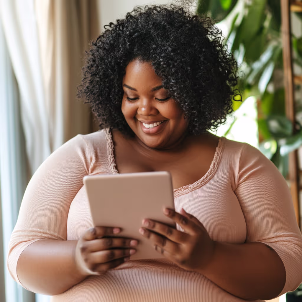 Woman smiling while using a tablet to explore Baddie Health