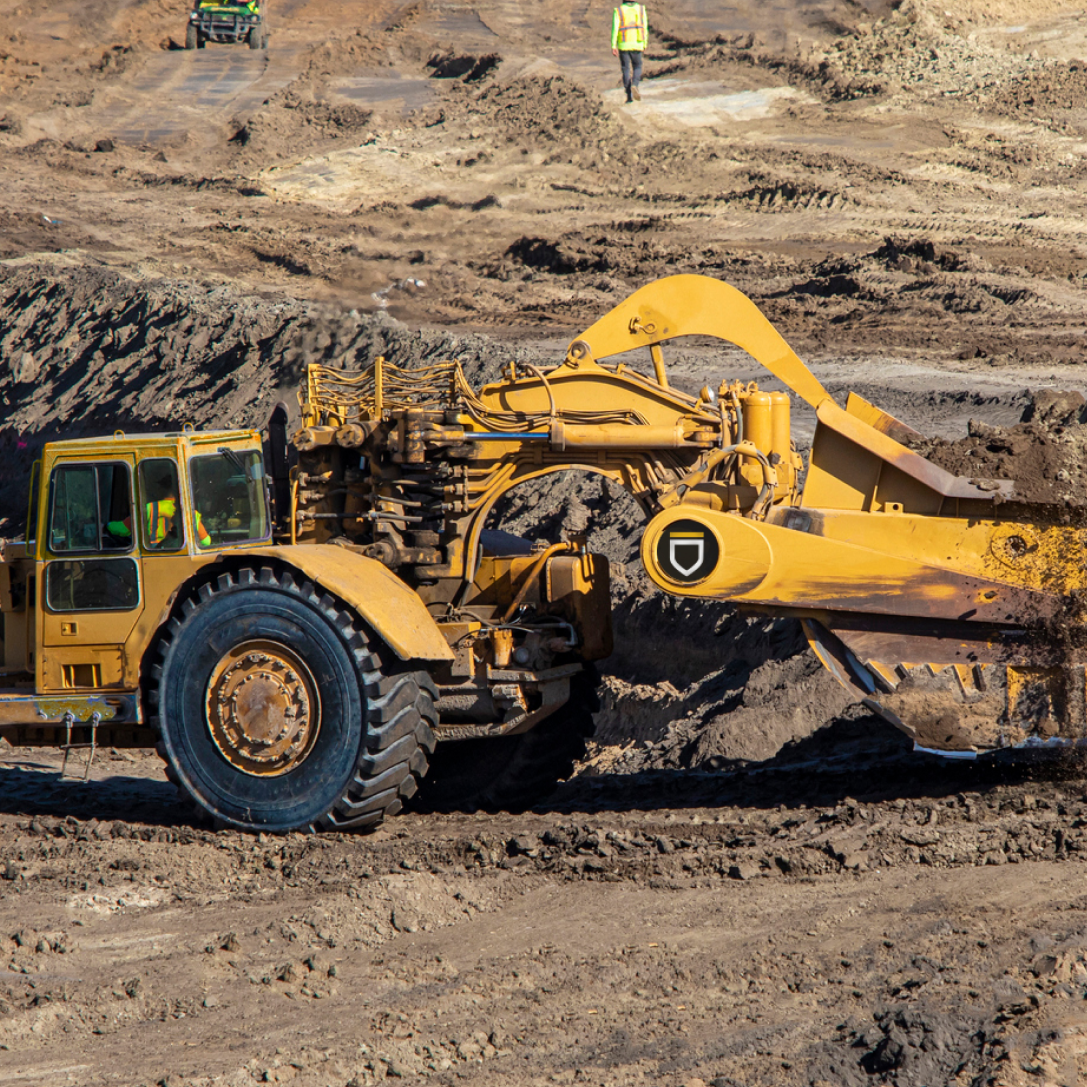 Kitstone Commons Bulk Earthmoving and Site Grading. Heavy-duty earthmoving equipment at work on a large-scale land development project. A scraper, used for cutting and transporting soil, operates on a construction site, demonstrating Ironclad Earthworks' capability in bulk earthmoving, land grading, and site preparation for infrastructure and residential projects.