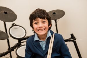 Young drummer happily learning fun drum lessons for kids