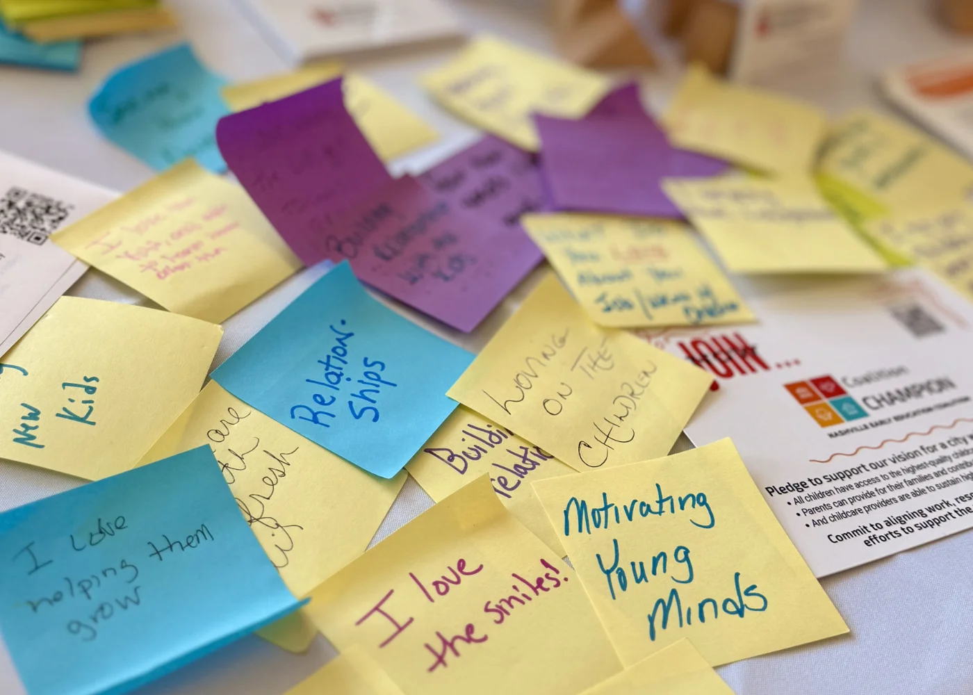 Colorful sticky notes with handwritten positive phrases about children and education scattered on a table.