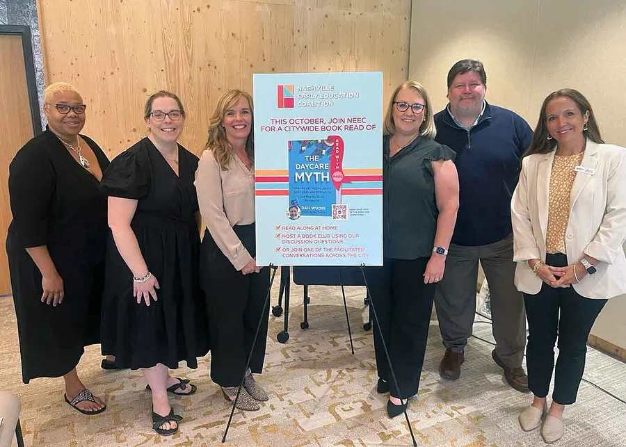 Six adults standing around a sign announcing a citywide book read of 'The Daycare Myth' hosted by Nashville Early Education Coalition.
