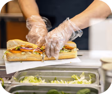 close up shot of an employee cutting a footlong Subway sandwich