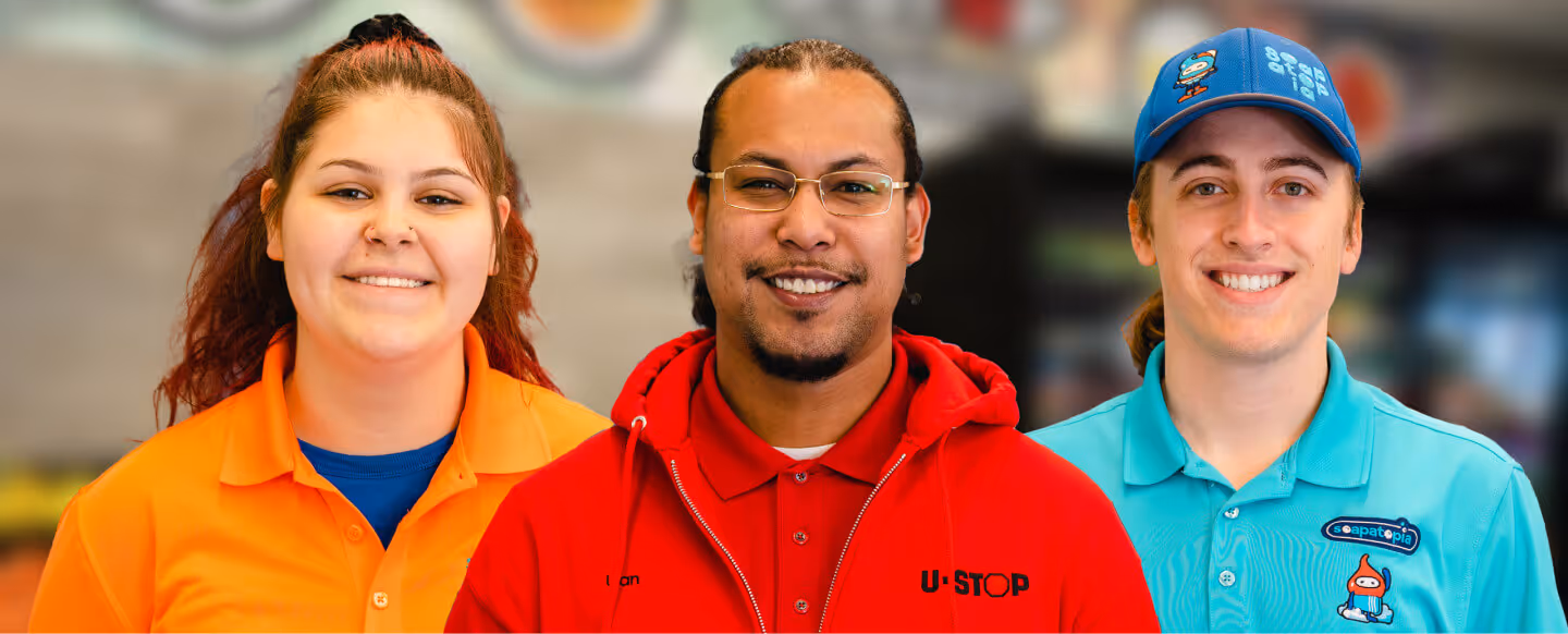portrait shot from left to right of a female Jeannie's Kitchen employee wearing a orange top, center is a male employee wearing a U-Stop Jacket, and to the right is a male employee wearing a Soapatopia employee outfit