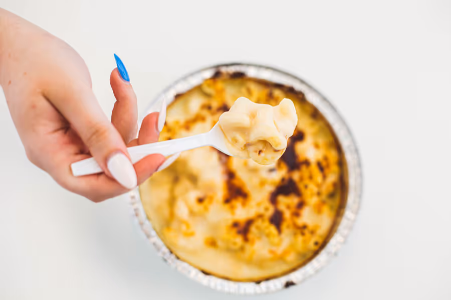 close up shot of a hand reaching in the Mac & Cheese bowl
