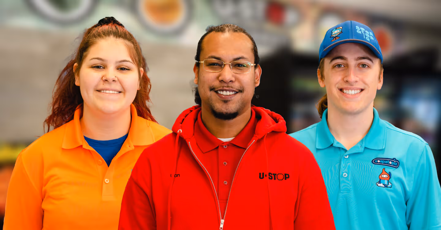 portrait shot from left to right of a female Jeannie's Kitchen employee wearing a orange top, center is a male employee wearing a U-Stop Jacket, and to the right is a male employee wearing a Soapatopia employee outfit