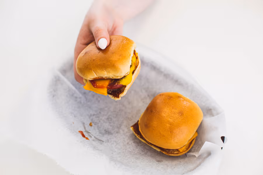 close up shot of a hand holding a cheeseburger 