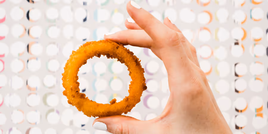 close up shot of a hand holding a onion ring