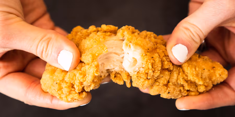 close up shot of a hand breaking chicken tender apart aesthetically