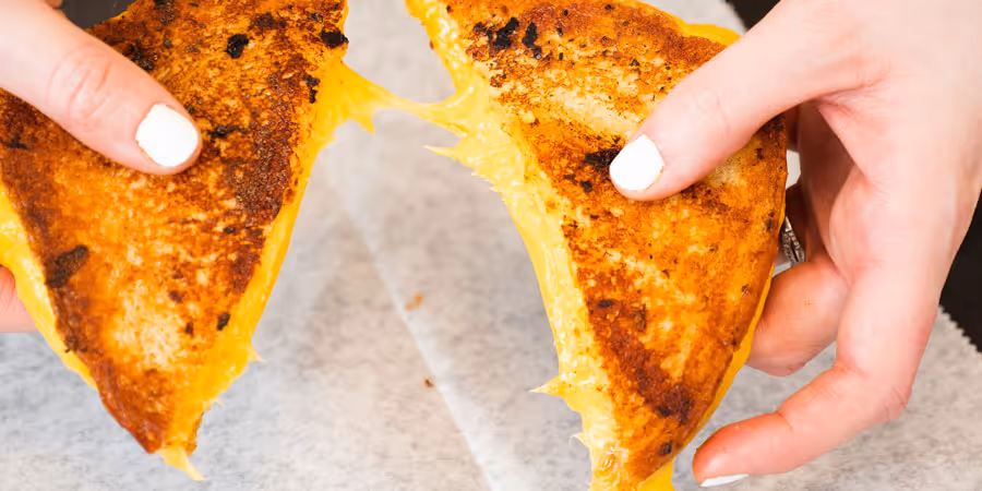 close up of a hand splitting a grilled cheese apart