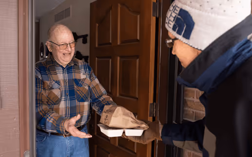 Elderly man receiving a meal from a delivery driver