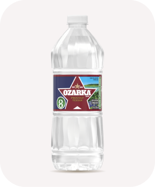 A clear plastic bottle of Ozarka water featuring a red label with a white star, proudly showcasing its Texan origin. The bottle is placed against a plain background.