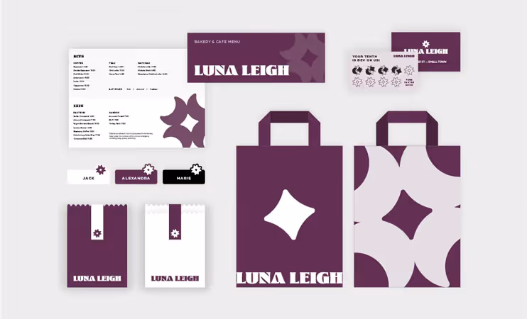 Collection of Luna Leigh bakery and cafe branded items including menu, business cards, loyalty cards, name tags, two paper bags with handles, and two paper snack bags with logo and purple design.