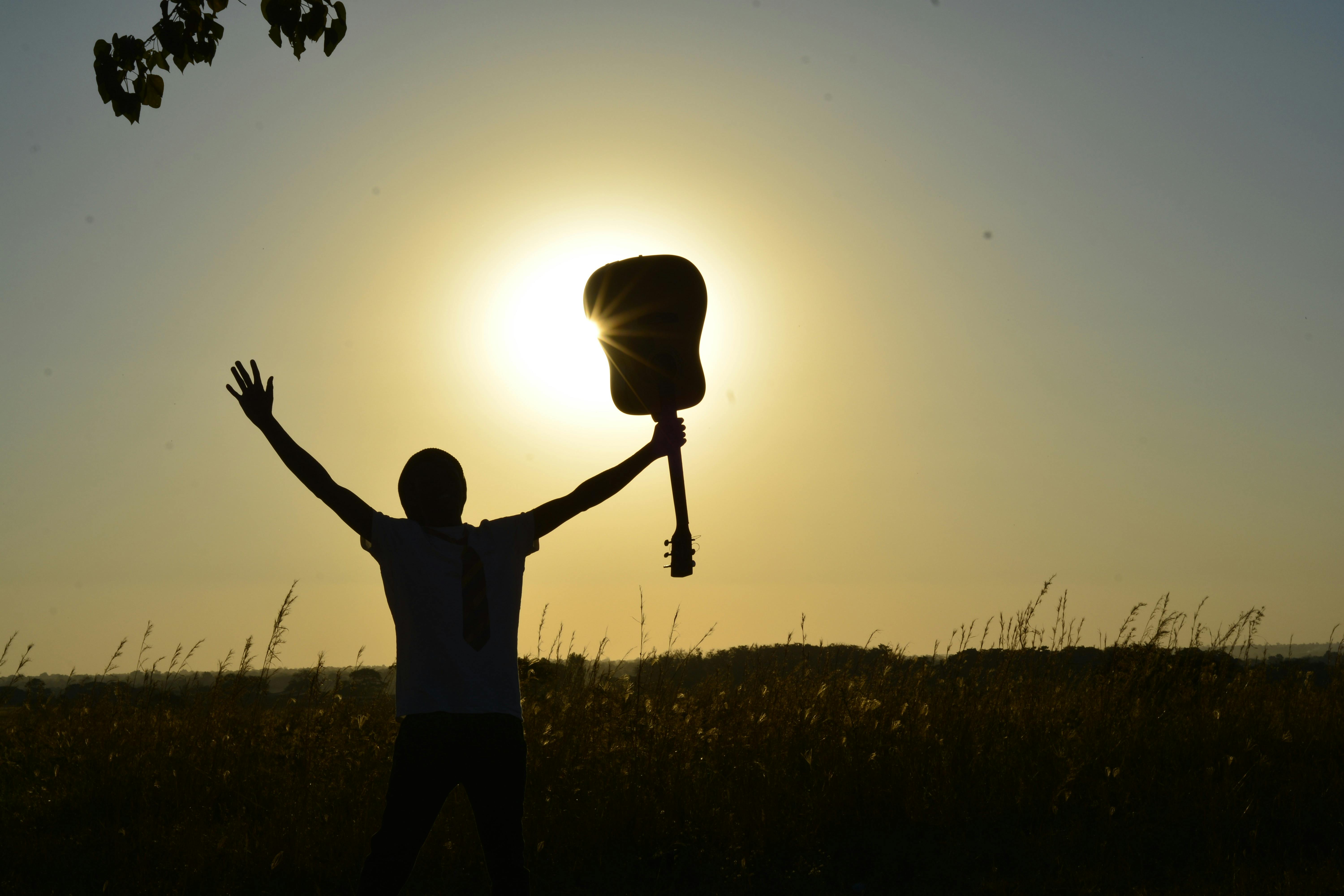 Man holding guitar with relief in the sunset
