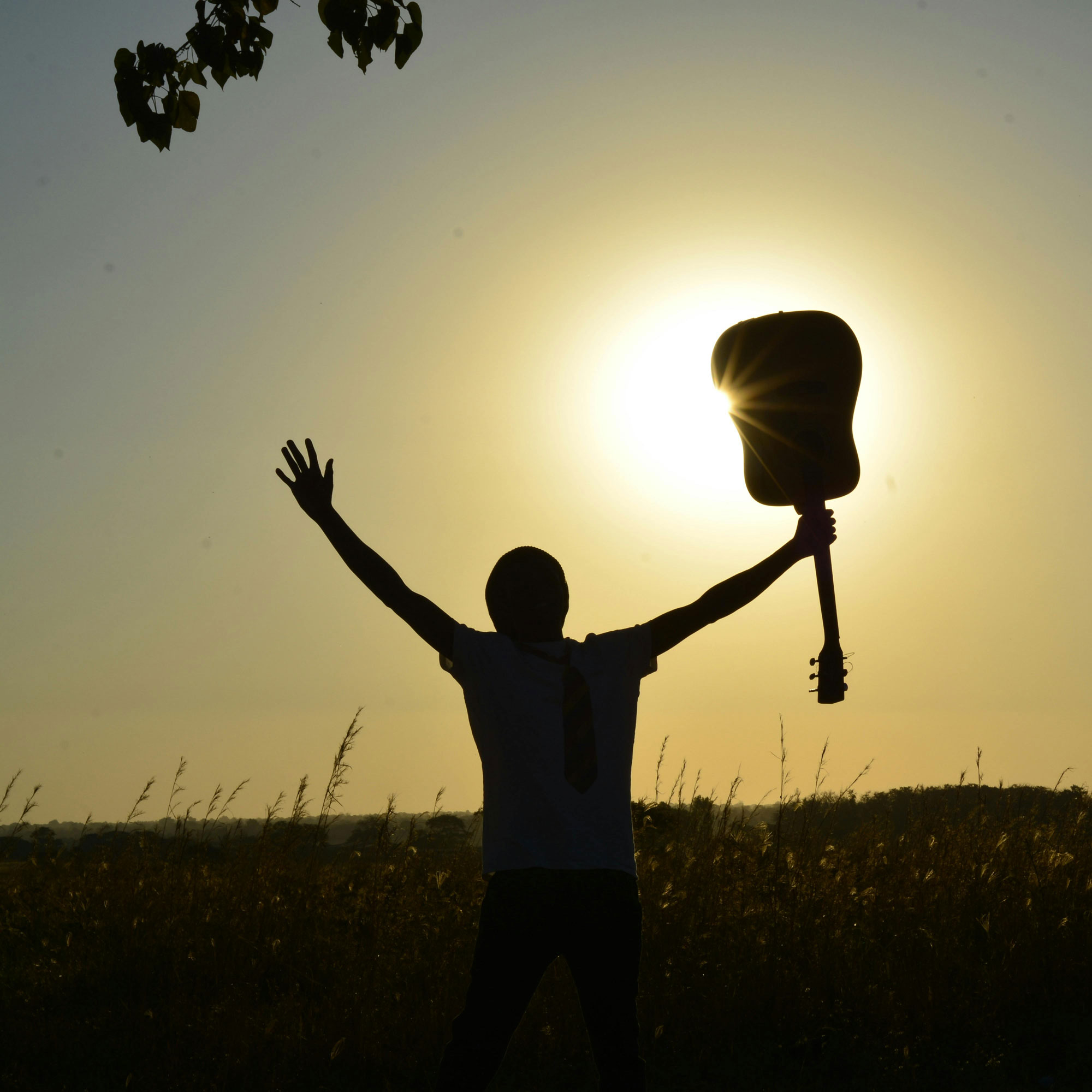 Man holding guitar with relief in the sunset