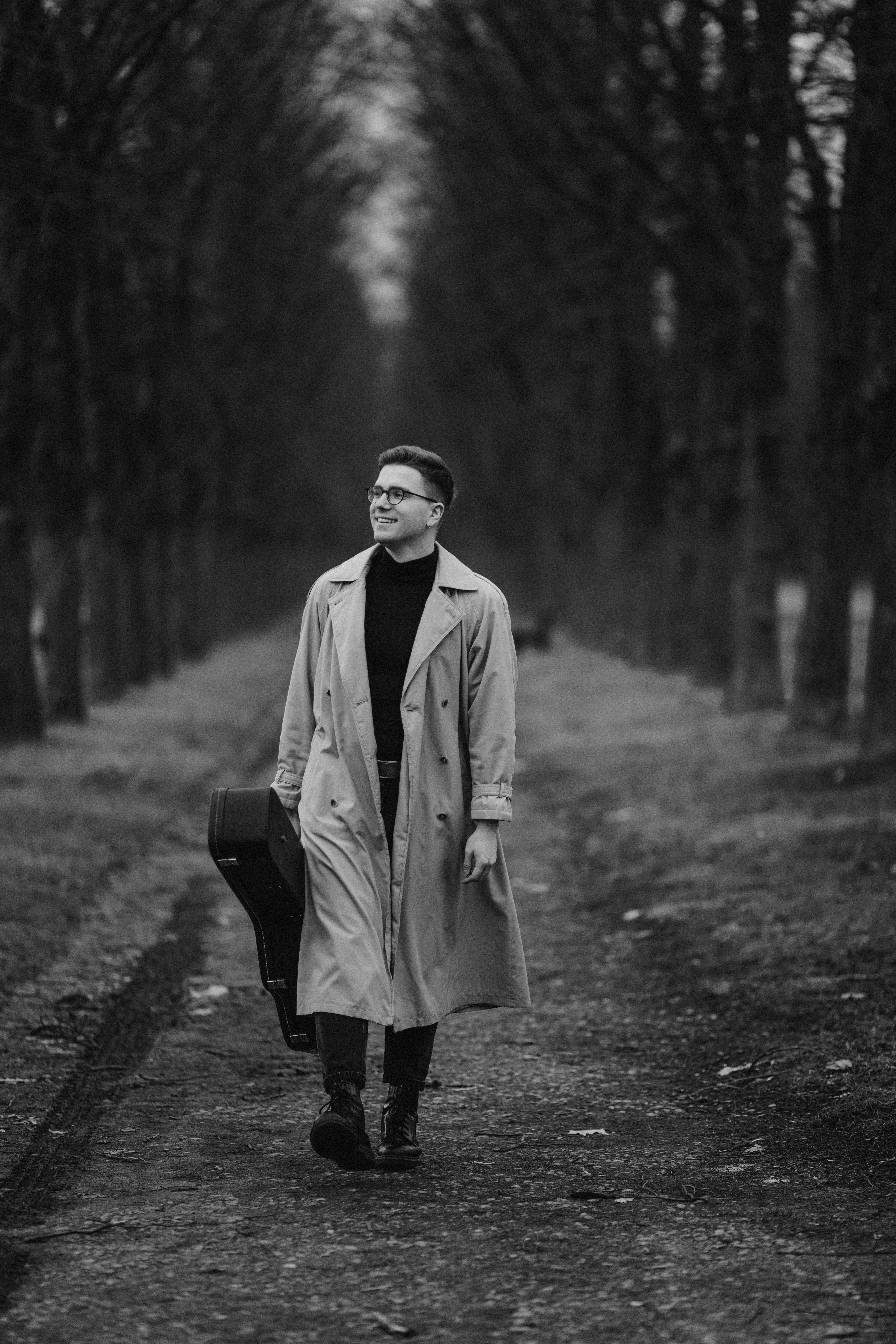 Man holding guitar on a path in the woods