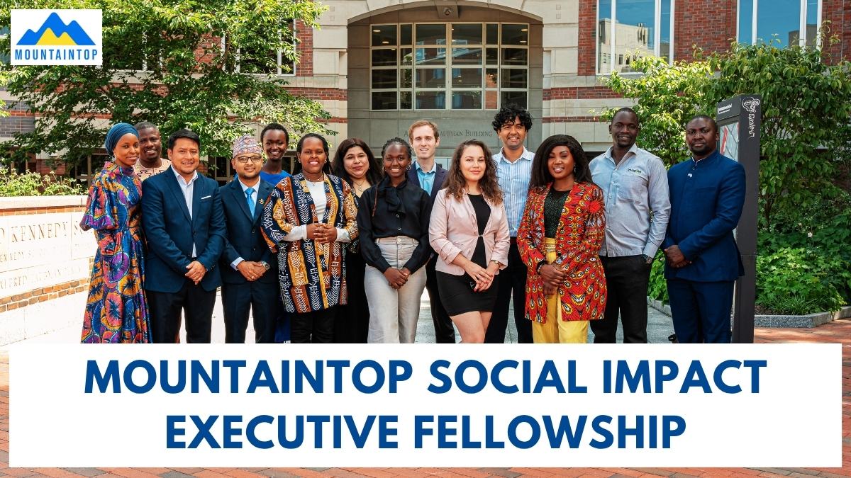 Group of Mountaintop Social Impact Executive Fellows posing outside Harvard Kennedy School with program banner below.