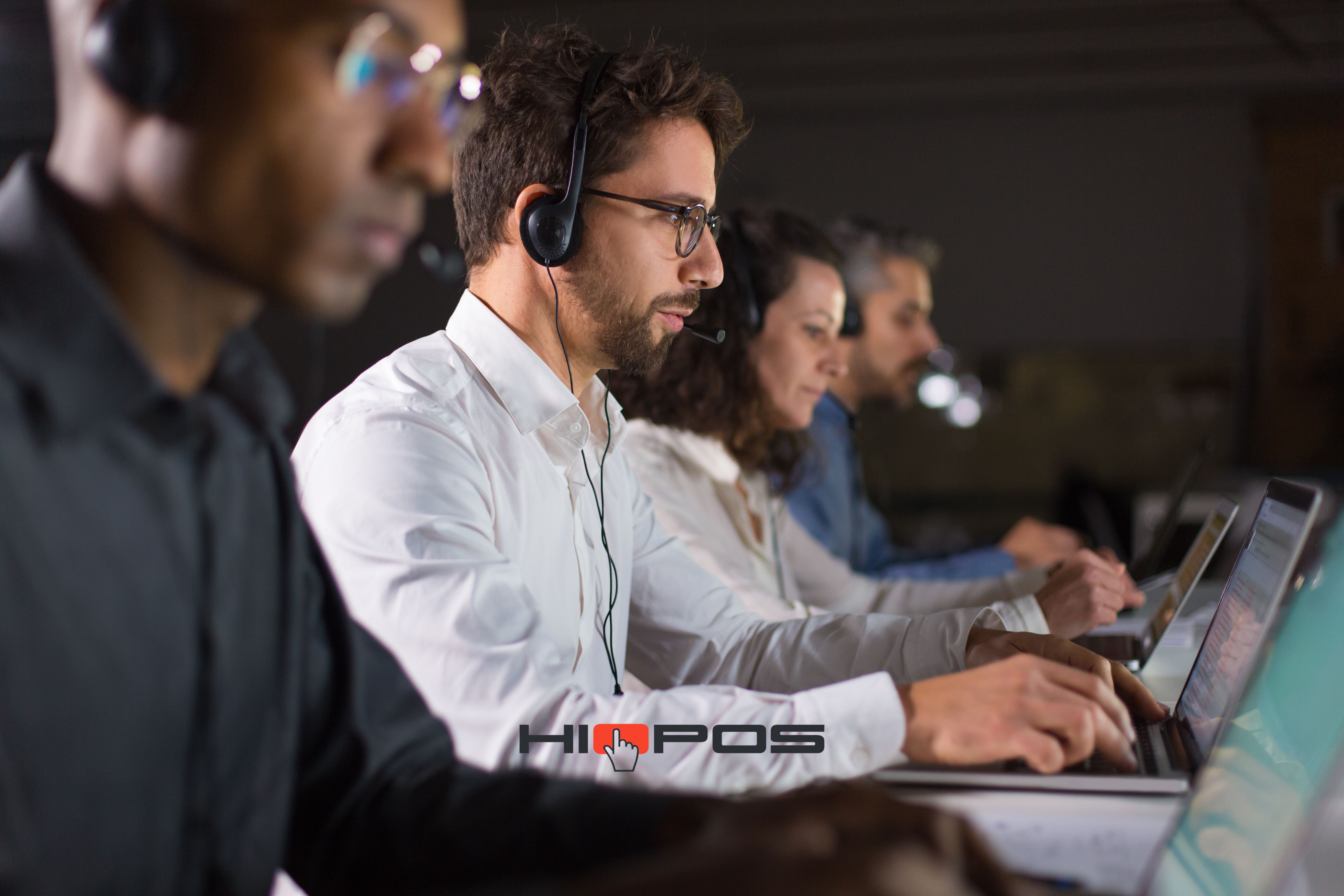 Equipo de soporte técnico usando auriculares y trabajando en laptops en una oficina.