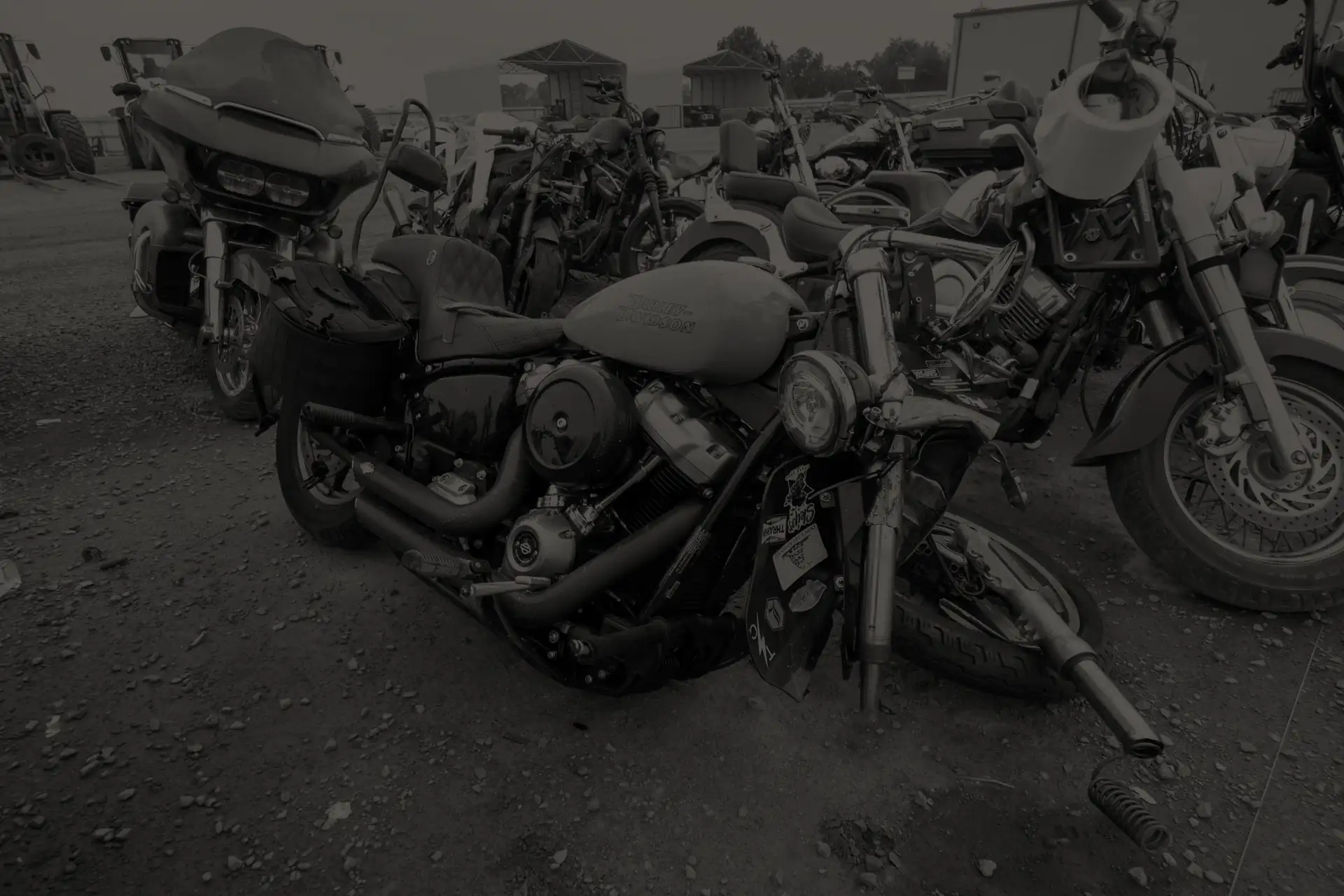Row of damaged motorcycles in San Diego salvage yard, with one fallen bike in front.